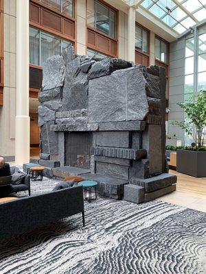 An amazing and unique granite clad fireplace sans chimney in center of great room.