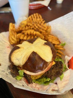 Single burger on a pretzel bun with waffle fries