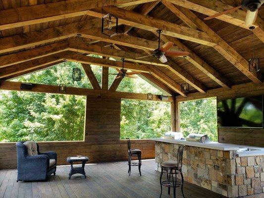 [Treehouse Vibes] Covered deck with outdoor kitchen wrapped in stone.