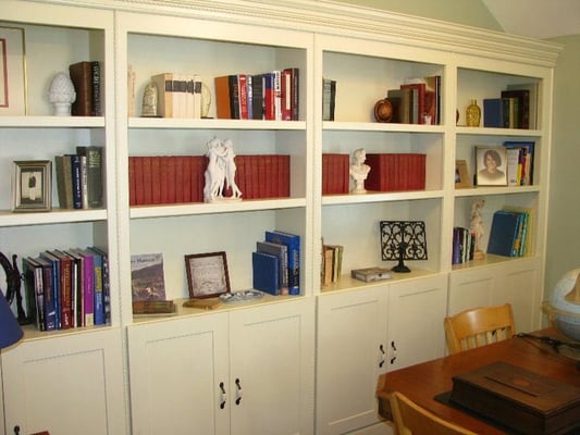 Library custom built shelving units with storage below wall to wall with multiple piece crown molding detail on top West Wareham