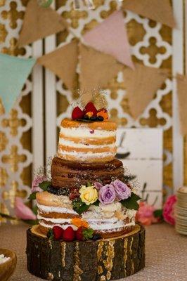 Naked wedding cake on wood slab.