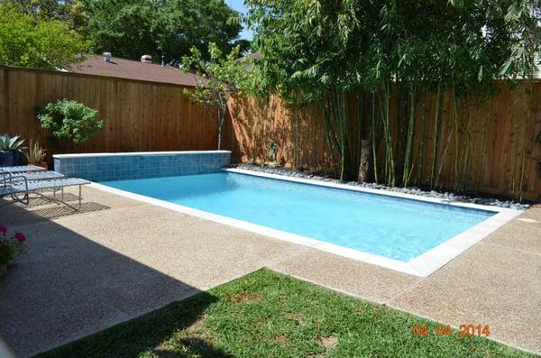 Classic geometric swimming pool, retention wall with water fall and extended deck. Peak Pools and Spas