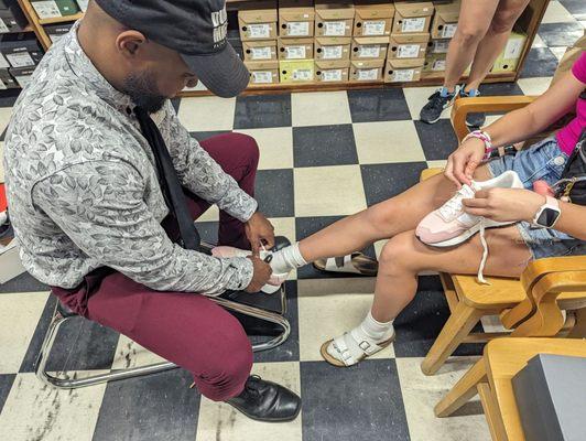 Store Manager Aaron helping our daughter try on shoes