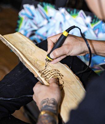 Local artist, Axel Cordero working on a wood piece one of the Maker's Markets that features some different local artists.