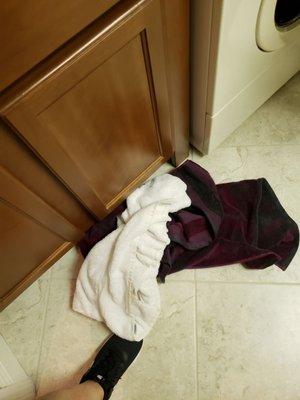 Dirty towels left on floor after the washing machine broke down.