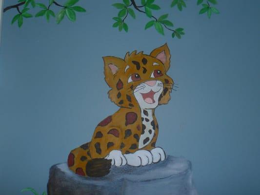 Nursery Mural with baby jaguar sitting on a rock under a branch.