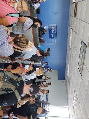 This is half the line of people waiting for service. People & luggage waiting outside in the hot sun. Only 3 people at the counter.