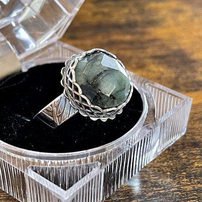 Faceted raw Emerald and sterling silver ring featuring a woven bezel and fern textured ring band.