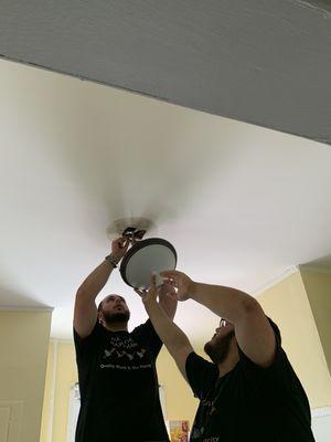 Team install of new light fixture in kitchen area