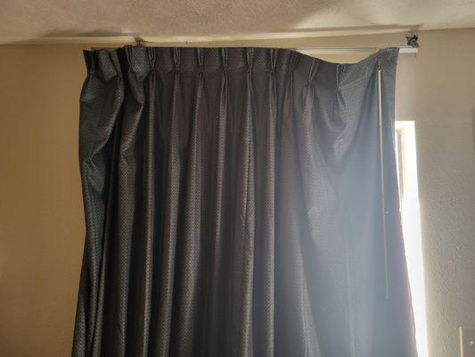 Curtain hanging in front hotel room window.  No one at this hotel cares to do things right.