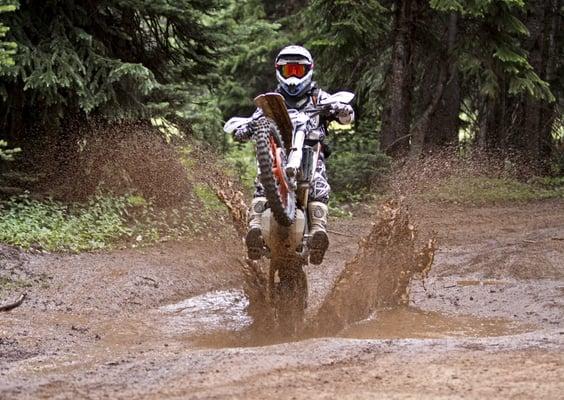 Head Coach Kiko Trincado demo'ing a wheelie through the mud on a ride with advanced students at the Aspen Dirtbike School