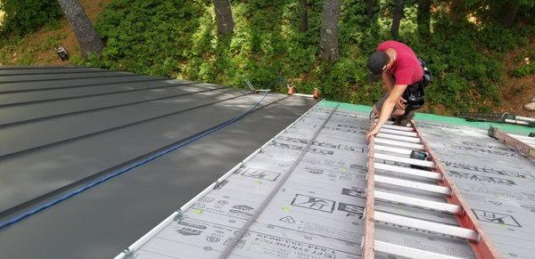 Roof panel being installed with a foam backer rod to reduce oil canning.  Classic Bronze Color.