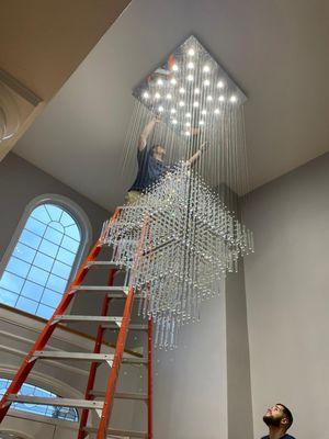 One of our experienced technicians installing a chandelier in a customers home. Want new lighting? "Just Call Landry!"