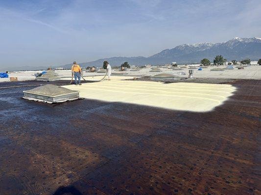 Applying polyurethane coating on roof prior to seal coating.