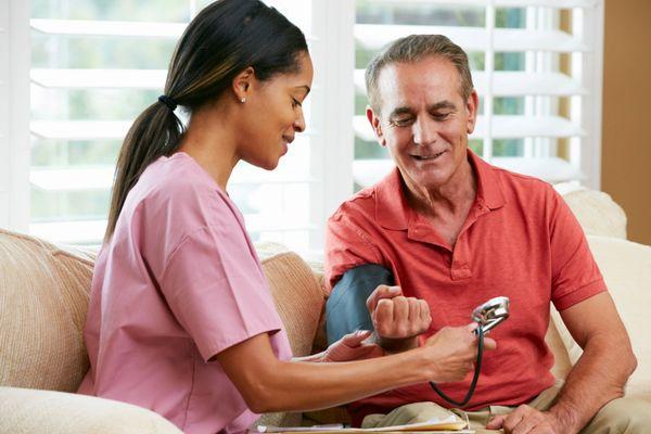 home health aide taking bloodpressure of male client.