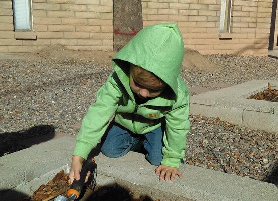 One of the preschoolers planting in the garden.