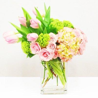 Suze-Lush hydrangea, spray roses, and tulips arranged beautifully in a glass rectangle.