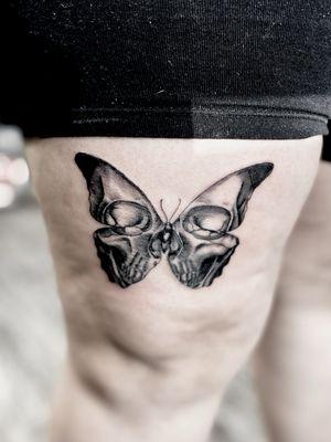 Skull with butterfly silhouette tattoo