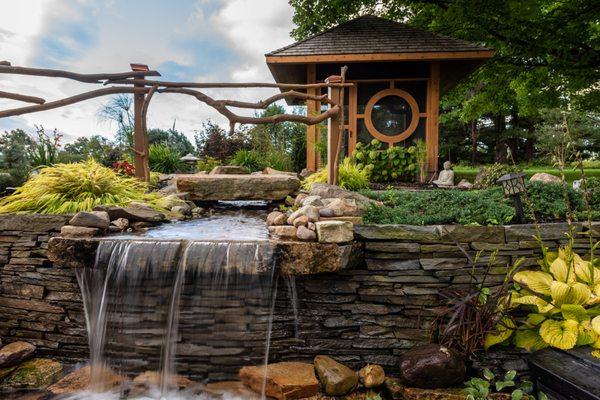 Tea house for yoga, stone bridge, waterfall over dry stack stone wall