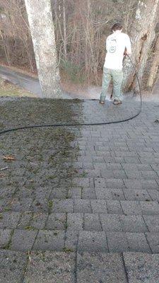 Pressure washing moss off a roof.