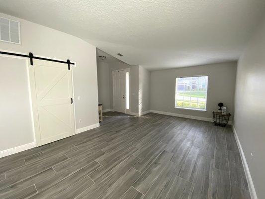 Removed Laminate & Tile Flooring, Installed new plank tiles and base boards, painted walls and ceiling, added new barn door . - After