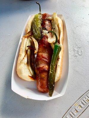 Street Dog wrapped in bacon with grilled onions, peppers and jalapeño