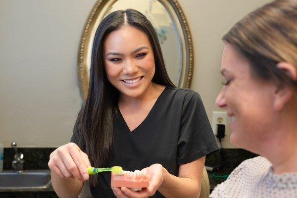 Our Registered Dental Hygienist showing a patient how to brush their teeth