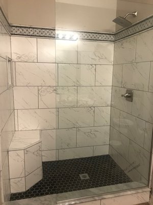 Shower renovation involving custom tile, glass shower panel, faucets, new linen closet, more