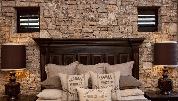 Dark stained shutters in the master suite. Small openings cased within a stacked rock wall.