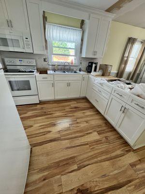 An entire kitchen remodeled new cabinets fresh, paint and laminate floor.