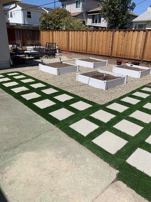 Pavers with artificial grass patio alongside a vegetable garden