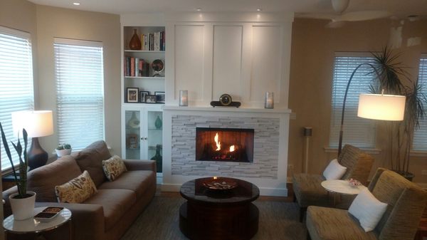 Custom cabinet and bookcase installed with glass doors and stacked stone tile.