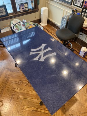 This is engineered stone with a Yankees emblem sandblasted into the surface   Glass protects the surface.