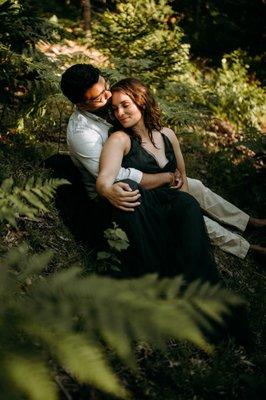 Couple cuddling outdoors in a field of ferns in Acadia National Park in Bar Harbor Maine