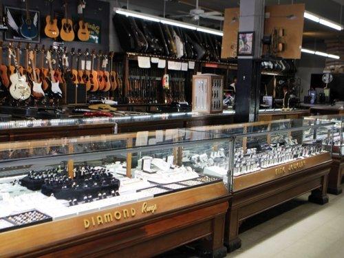 Part of our extensive jewelry counter with a view of our gun rack and guitar wall