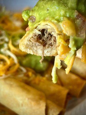 Shredded Beef Rolled Tacos with Guacamole and Cheese.