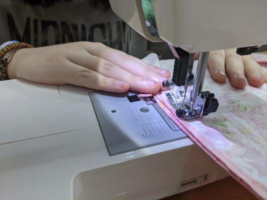 A student sewing together two pieces of fabric.