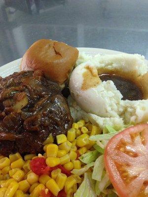 Hamburger steak, mashed potatoes and gravy, corn, salad, and dinner roll