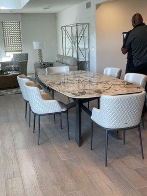 New dining room table and chairs and chrome and glass storage unit behind existing couch.