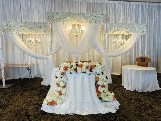 Back drop with chandeliers and sweet heart table with floral garland