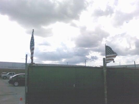 The American Flags marking the entrance to the lot.  Both are in bad condition, one is literally 1/2 torn away.