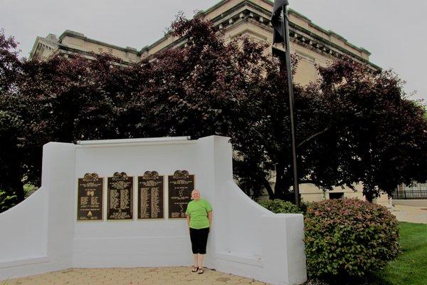 Scruffy person in front of nice memorial.