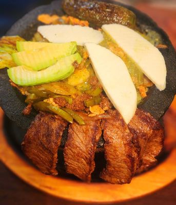 MOLCAJETE,FAJITA CHICKEN,SHRIMP & CHORIZO, PEPPERS & ONIONS,CATCUS LEAF,SALSA VERDE & CHEESE, RICE, REFRIED BEANS,GUACAMOLE,SOUR CREAM