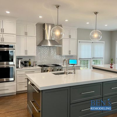 a remodeled kitchen with wooden floor, white cabinet, grey cabinet island, white quartz countertop, pendant & recessed lighting