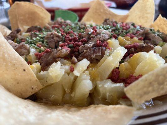 Baked potato with bacon bits cheese and chives topped with molleja.