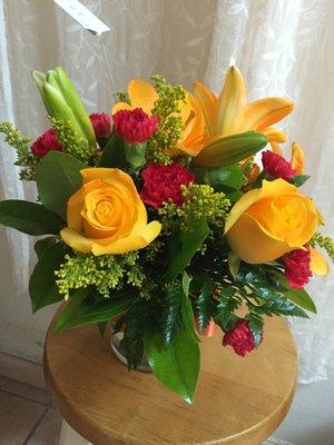 Festive fall bouquet with yellow lilies and roses and red carnations.