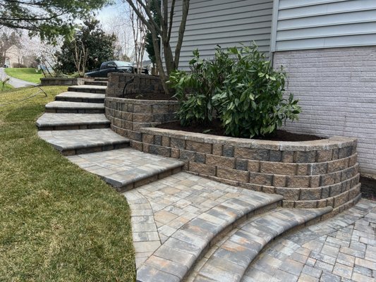 Graceful steps with raised planter beds lead to a gorgeous new patio.