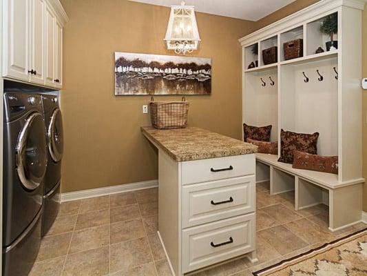 Wall color and custom cabinetry in this laundry room, equipped with a built in center island for easy folding and storage.