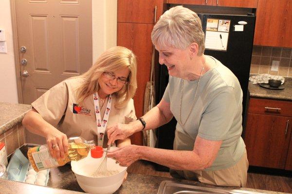 Caring Senior Service caregiver helping a client bake a cake