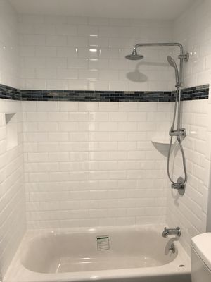 A kids bathroom tub surround with beveled 4x8 subway tile and glass mosaic accents